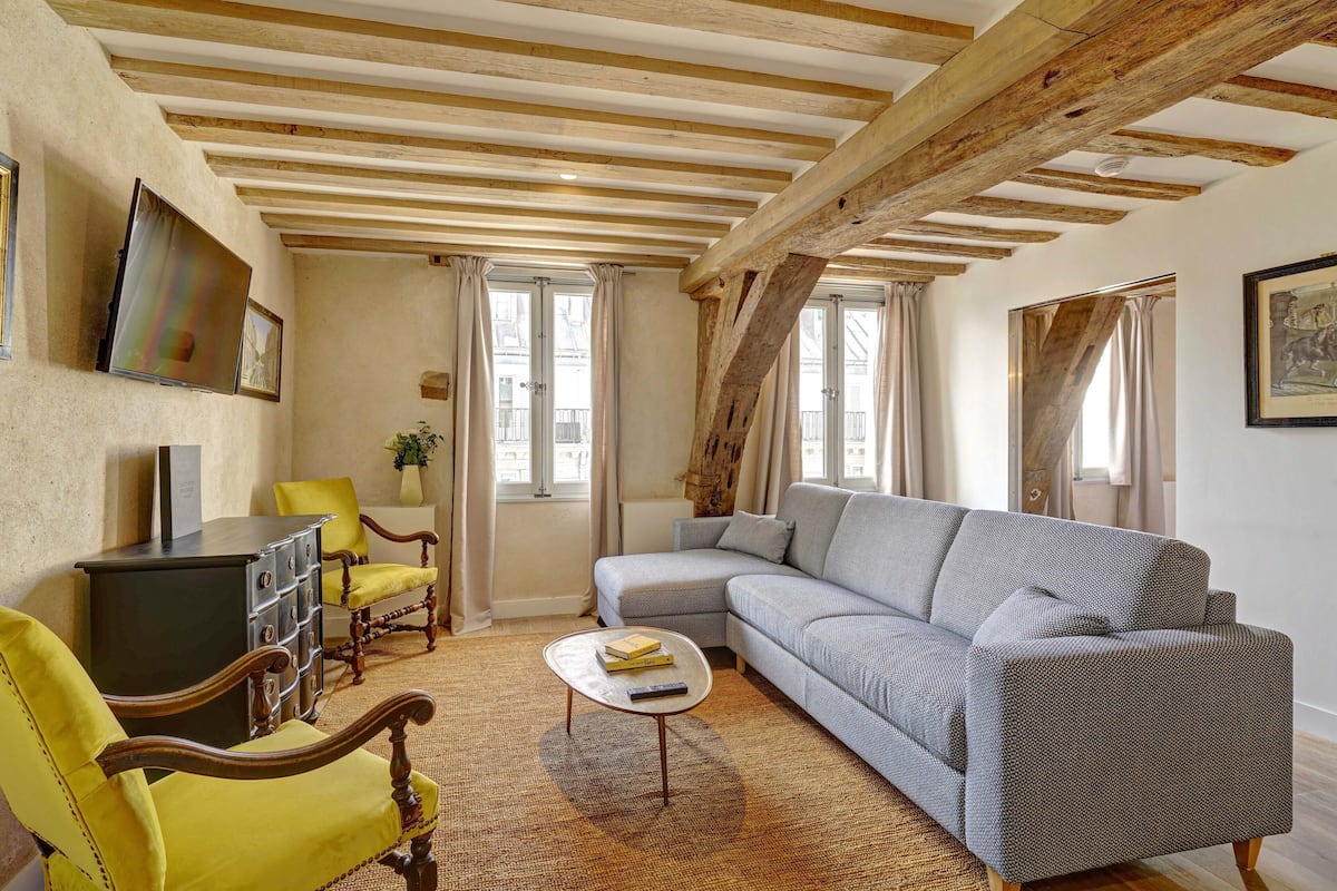 A living room with a sofa, armchairs, a coffee table, and a TV on a stand.