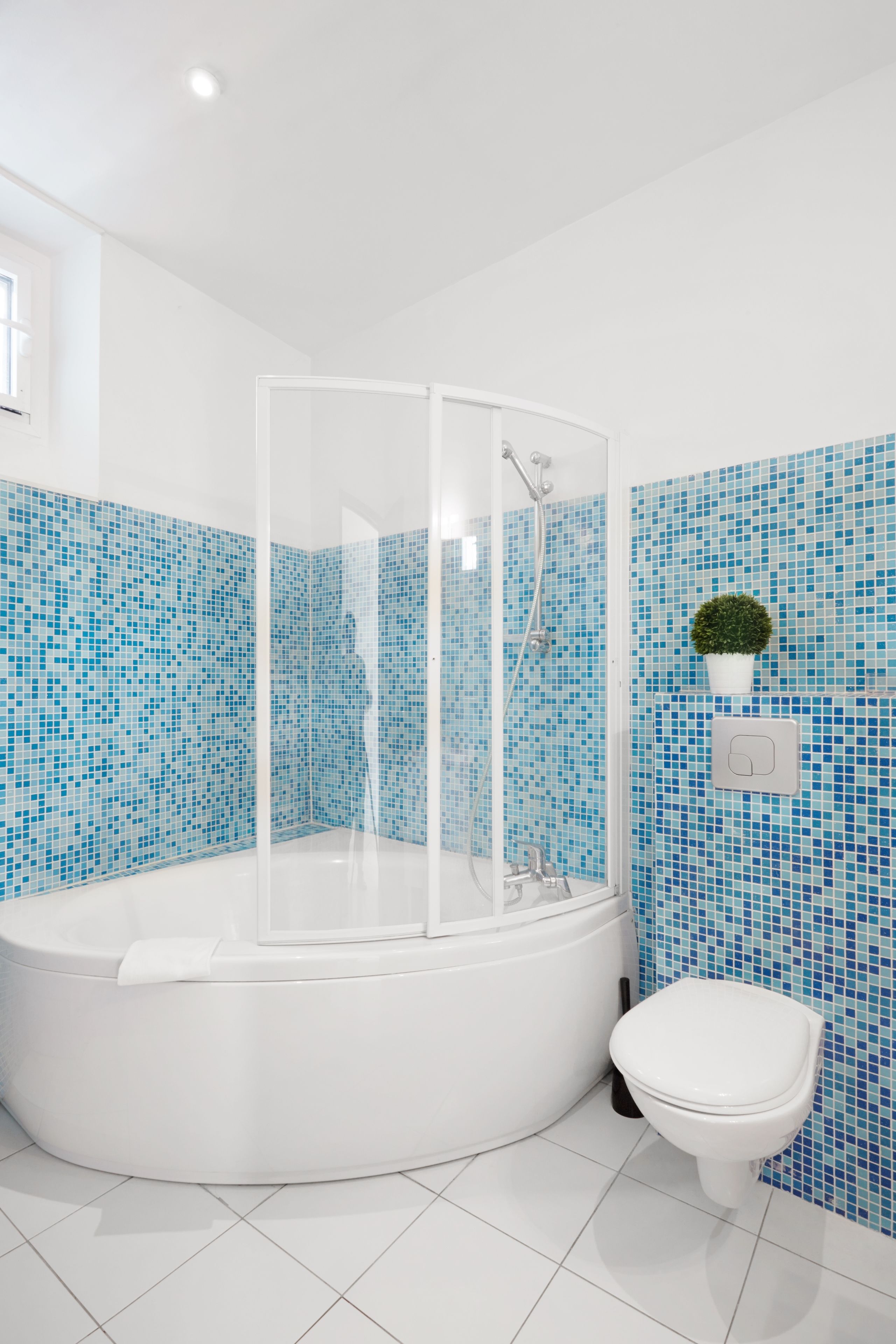 A bathroom with a glass-enclosed shower, a white bathtub, and a toilet.