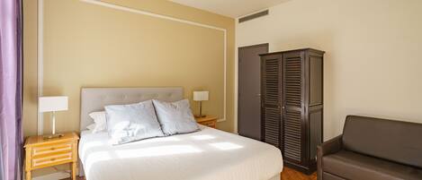 A bedroom with a bed, bedside tables, a wardrobe, and a sofa.