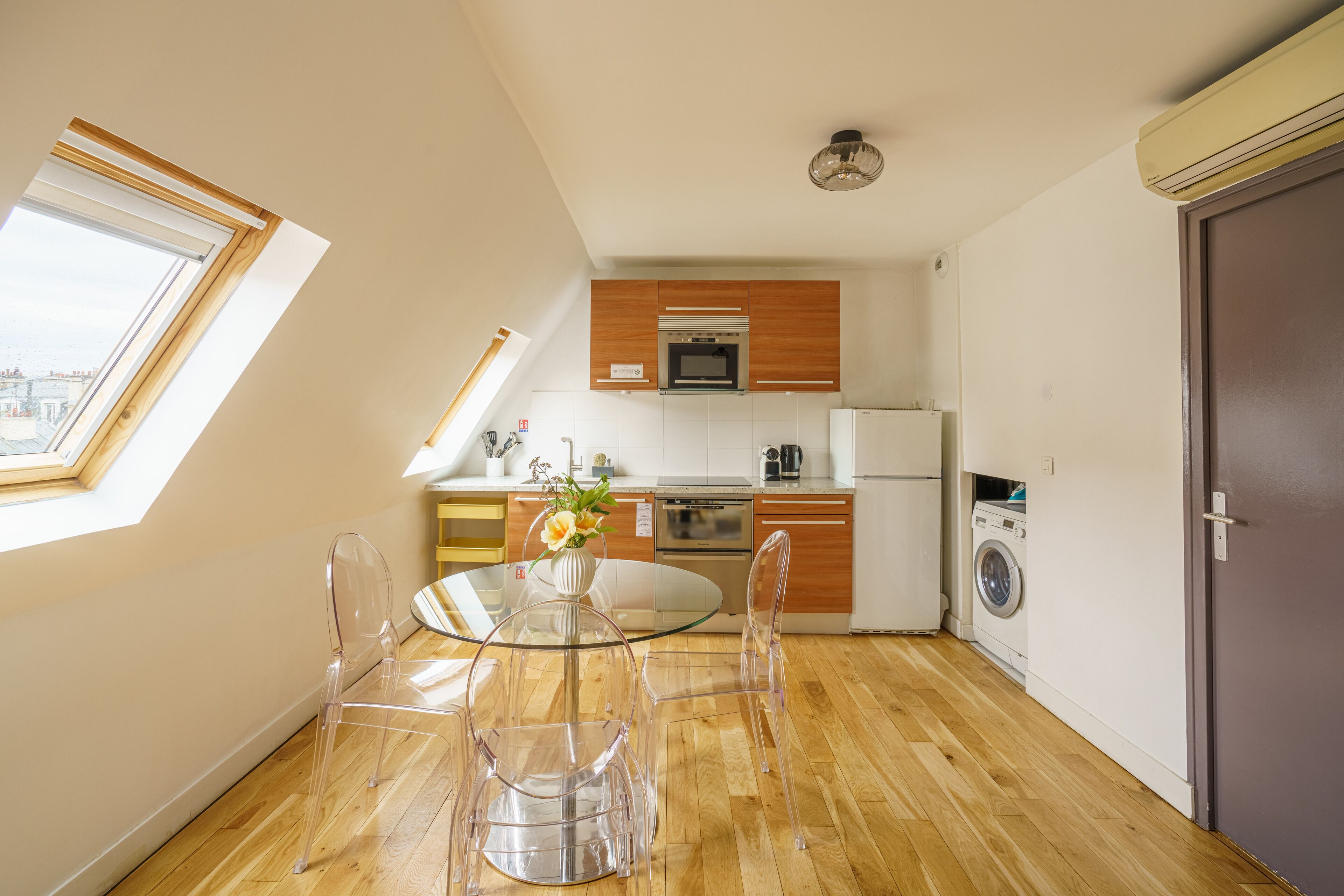 A modern kitchen with wooden cabinets, a built-in oven, microwave, and a washing machine.