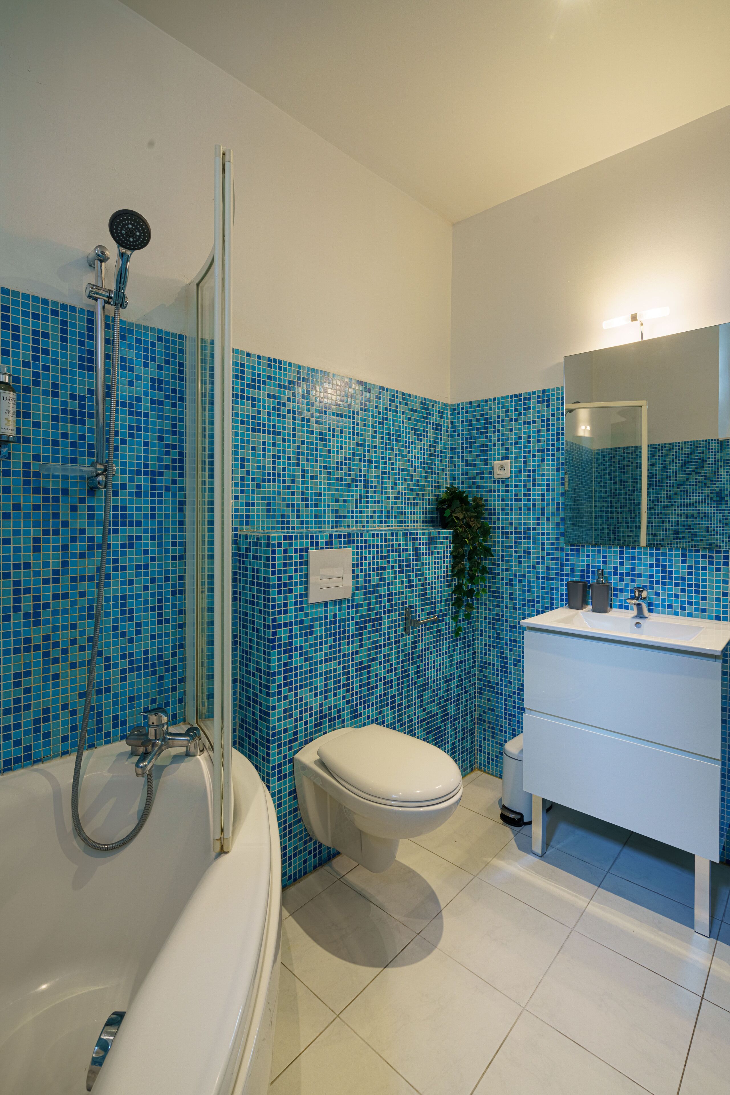 Een badkamer met een bad, toilet, wastafel en een douche met een glazen deur.