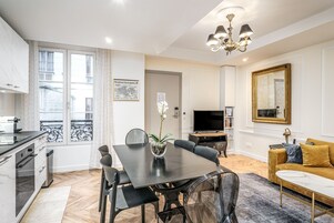 A modern living room with a dining table, sofa, and TV.