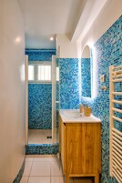 Un baño con ducha de azulejos, tocador de madera y lavabo blanco.