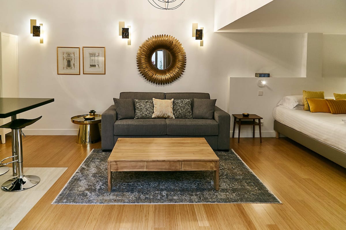 A modern living room with a sofa, coffee table, and a round mirror on the wall.