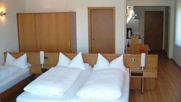 Een hotelkamer met twee eenpersoonsbedden, houten kasten, een klein bureau en een badkamer zichtbaar door een open deur.