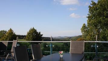Una terraza con mesa y sillas, con vistas a un paisaje pintoresco.