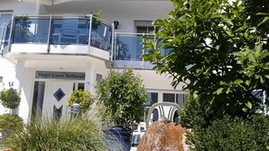 A hotel named "Hotel Garni Retterat" with a balcony, surrounded by lush greenery and red flowers. - Hotel Retterath am Nürburgring (Wiesemscheid)