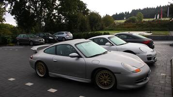 A parking lot with several parked cars, including a silver sports car in the foreground.