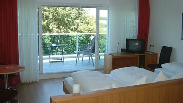 A hotel room with a bed, a desk with a television, a chair, and a table.