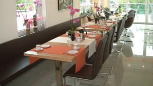 A dining area with long tables, chairs, and a bench. - Hotel Retterath am Nürburgring (Wiesemscheid)