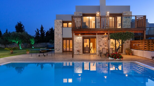 Una casa moderna de dos pisos con una piscina al frente.