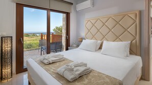 Habitación de hotel con una cama grande, vistas al mar y un balcón con mesa y sillas.