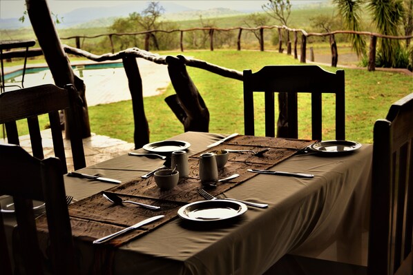 Una mesa de comedor al aire libre con sillas, platos, cubiertos y una jarra.