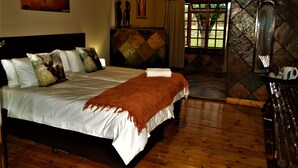 Un dormitorio con cama, un cuadro en la pared, una ventana con cortinas y un muro de piedra.
