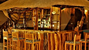 Una zona de bar con sillas de madera y techo de paja.