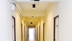 A long, narrow hallway with doors on both sides, leading to individual rooms. - Budsarakam Place Hotel (Chanthaburi)