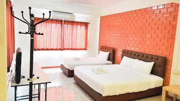 A hotel room with two beds, a desk with a computer, and a brick-patterned wall.