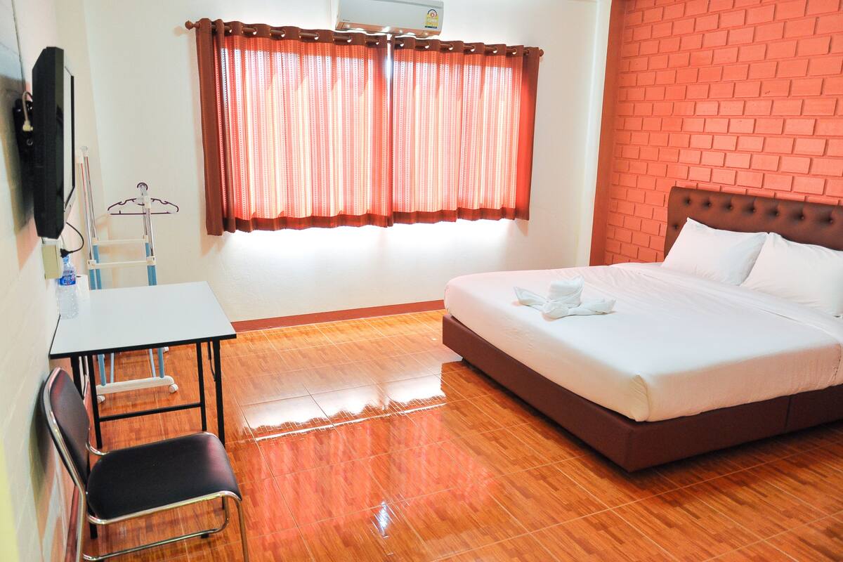A hotel room with a bed, a desk, a chair, and a window with curtains.
