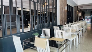A modern restaurant with a long counter, white chairs, and a glass partition. - The Grand Day Night (Pattaya)