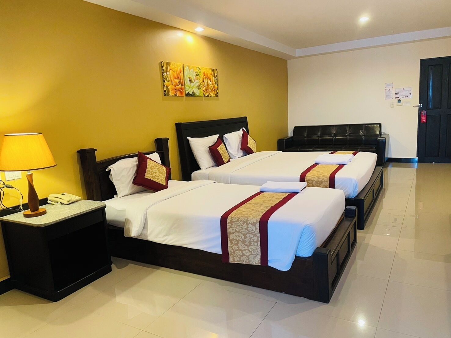 A hotel room with two beds, a nightstand with a lamp, and a painting on the wall.