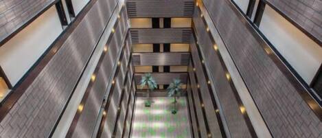 A multi-level atrium with a central open space featuring a patterned floor and potted plants.