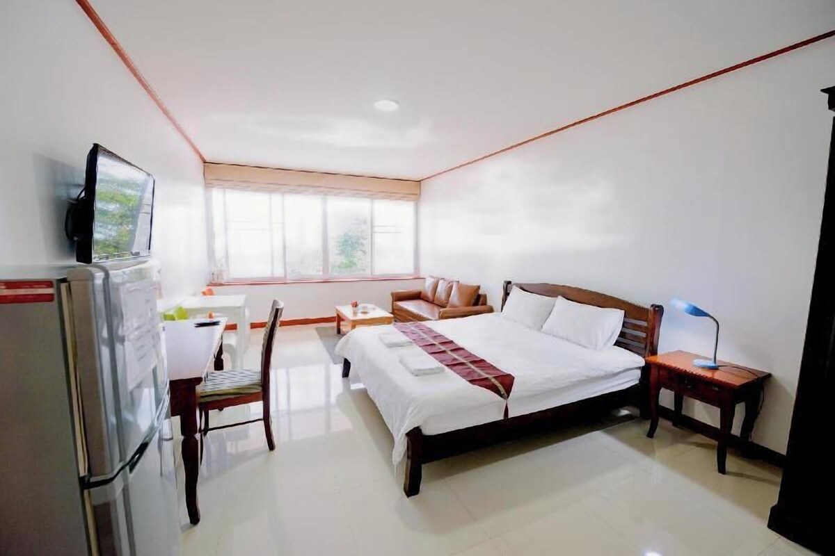 Habitación de hotel con cama, escritorio, silla, televisión y ventana.