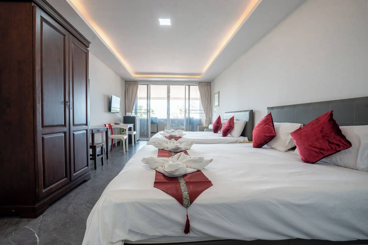 Une chambre d’hôtel avec deux lits, un bureau et une télévision.