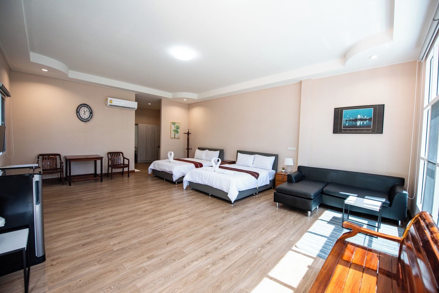 A hotel room with two beds, a sofa, a desk, and a chair.