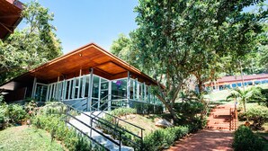 Un bâtiment moderne doté d’une façade en verre, d’un toit en bois et d’un escalier menant à l’entrée.