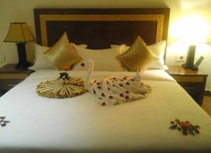 A neatly made bed with a swan-shaped centerpiece and decorative pillows.