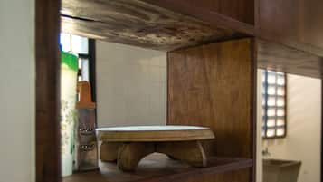 Una cocina con estantes de madera, una tabla de cortar blanca, un colador metálico y un tazón de madera.
