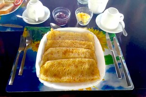 A plate of crepes with a side of fruit and condiments.