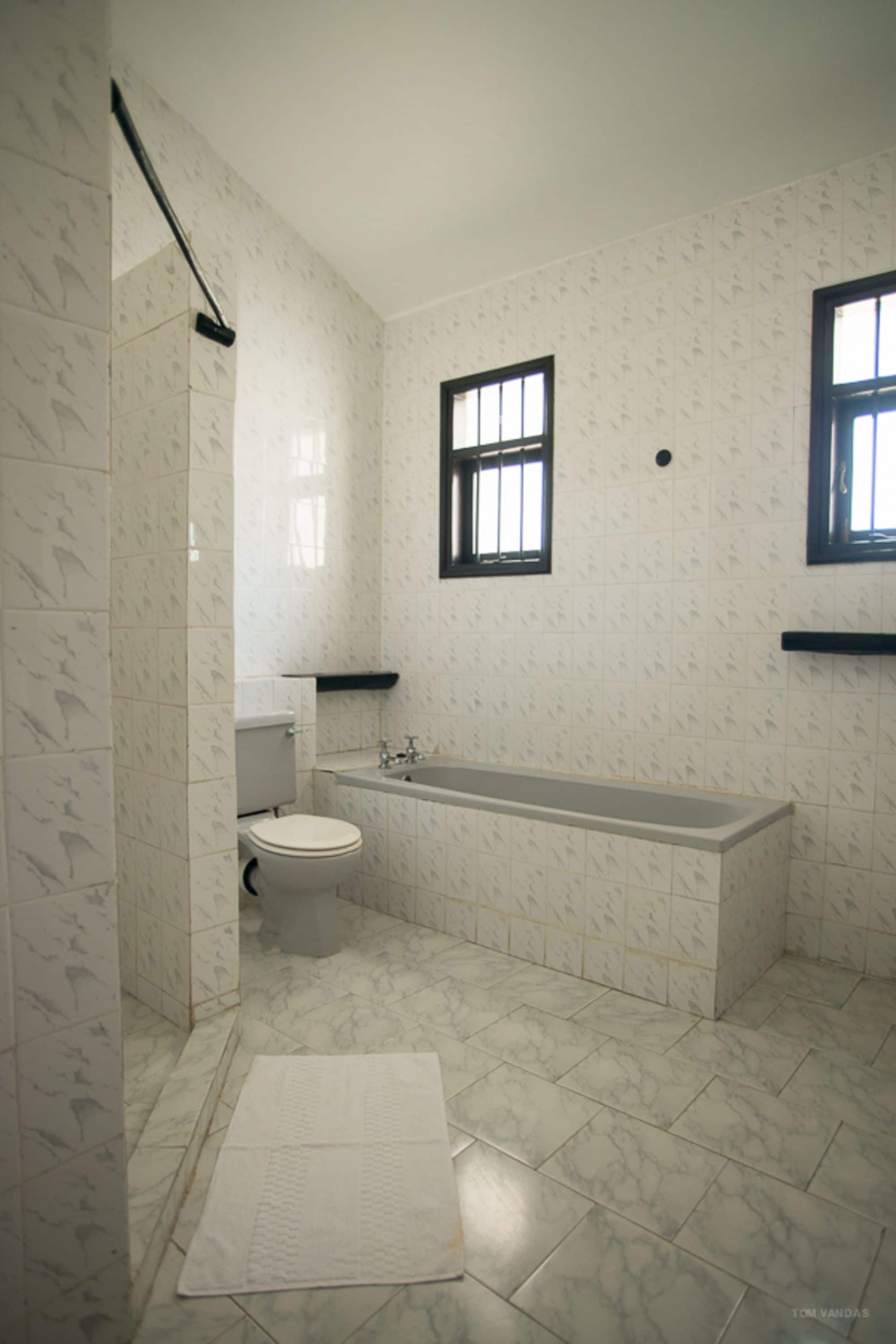A bathroom with a toilet, bathtub, and a window.