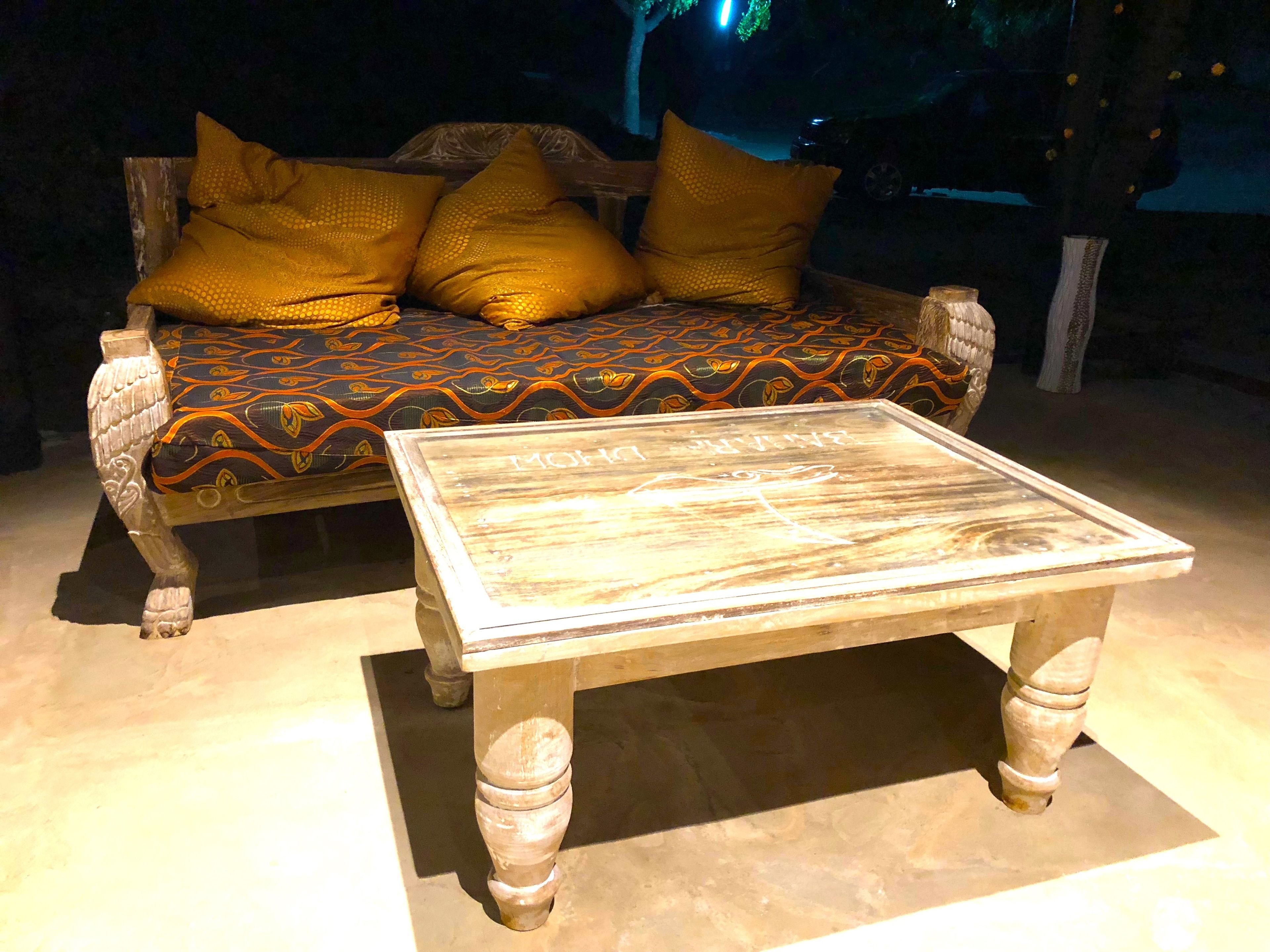 Una mesa de centro de madera con una superficie de mármol y un sofá con cojines estampados.
