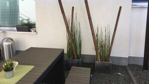 A patio area with a table, potted plants, and a bamboo structure. - WohnRaum Hotel & Gästehaus (Gusterath)