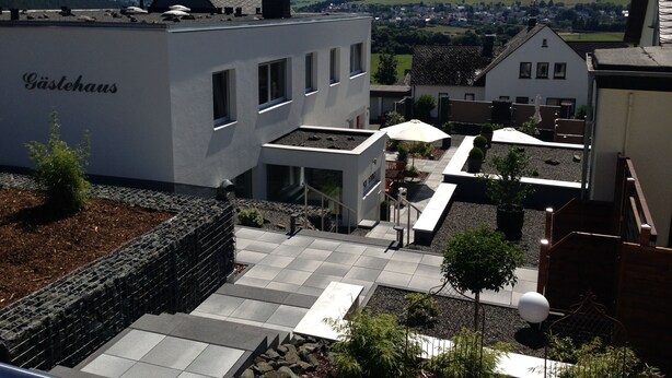 A building with a sign reading "Gästehaus" and a courtyard with outdoor seating and plants. - WohnRaum Hotel & Gästehaus (Gusterath)