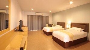A hotel room with two beds, a desk, a mirror, and a TV. - Paragon Suites Resort (Pattaya)