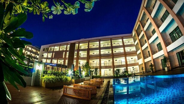 A multi-story hotel with a pool area, outdoor seating, and a well-lit facade. - Paragon Suites Resort (Pattaya)