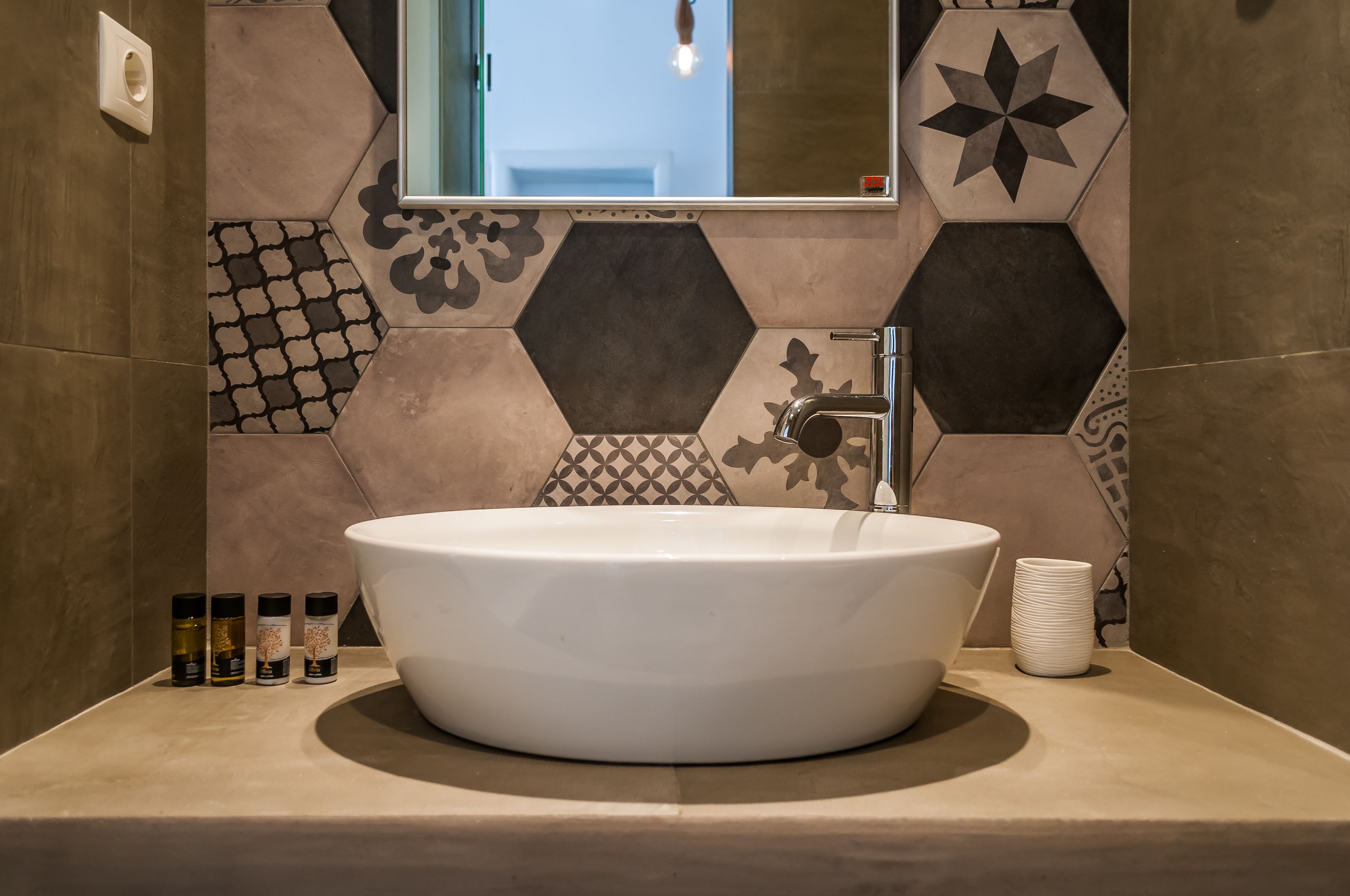A bathroom with a large oval sink, a mirror, and hexagonal patterned tiles.