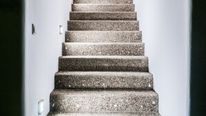 A staircase leading up to a room with a light fixture at the top. - Vilos Suites (Milos)