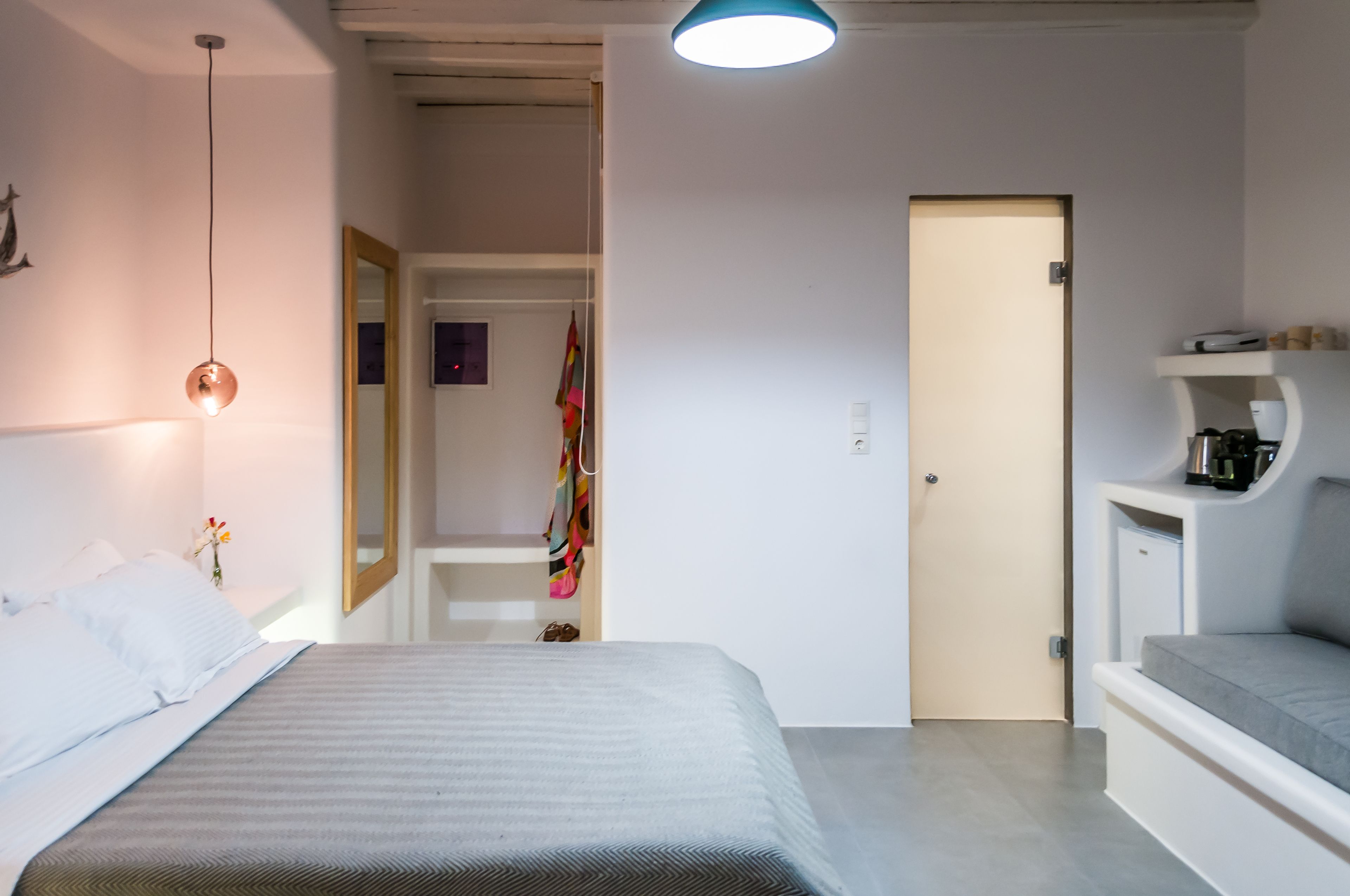 Una habitación de hotel moderna con una cama, mesita de noche y un pequeño rincón de descanso con sofá.