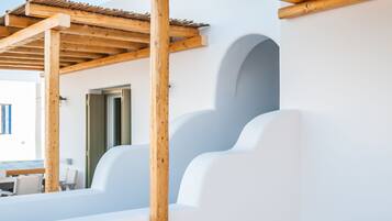 Una terraza moderna al aire libre con una pérgola de madera, paredes blancas y suelo de baldosas.
