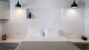 Un dormitorio minimalista con una cama, dos lámparas colgantes y una estantería con botellas.