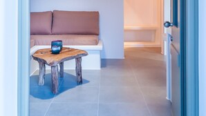 A modern interior with a wooden table, a bench, and a hanging light fixture. - Vilos Suites (Milos)