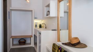A compact kitchen with a sink, a coffee machine, and a hanging light fixture.