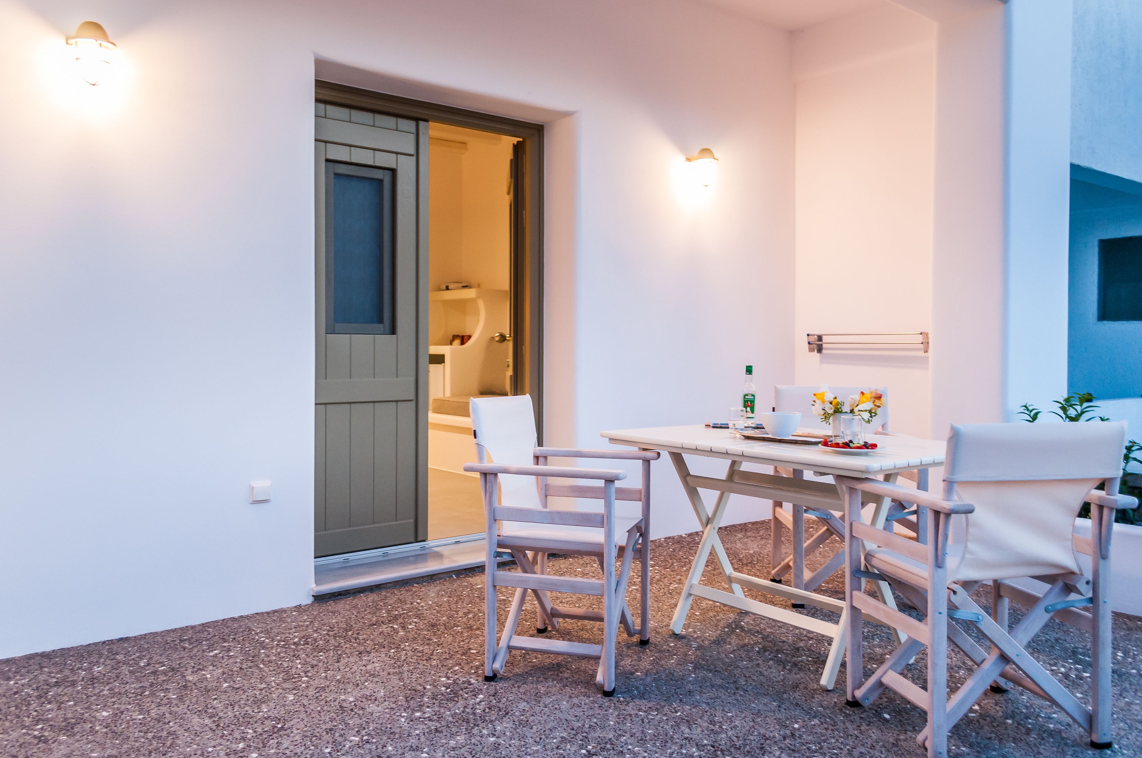 Une petite terrasse avec une table et des chaises, une porte donnant accès à une salle de bain et un porte-serviettes fixé au mur.