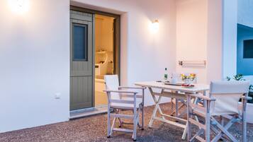 Une petite terrasse avec une table et des chaises, une porte donnant accès à une salle de bain et un porte-serviettes fixé au mur.