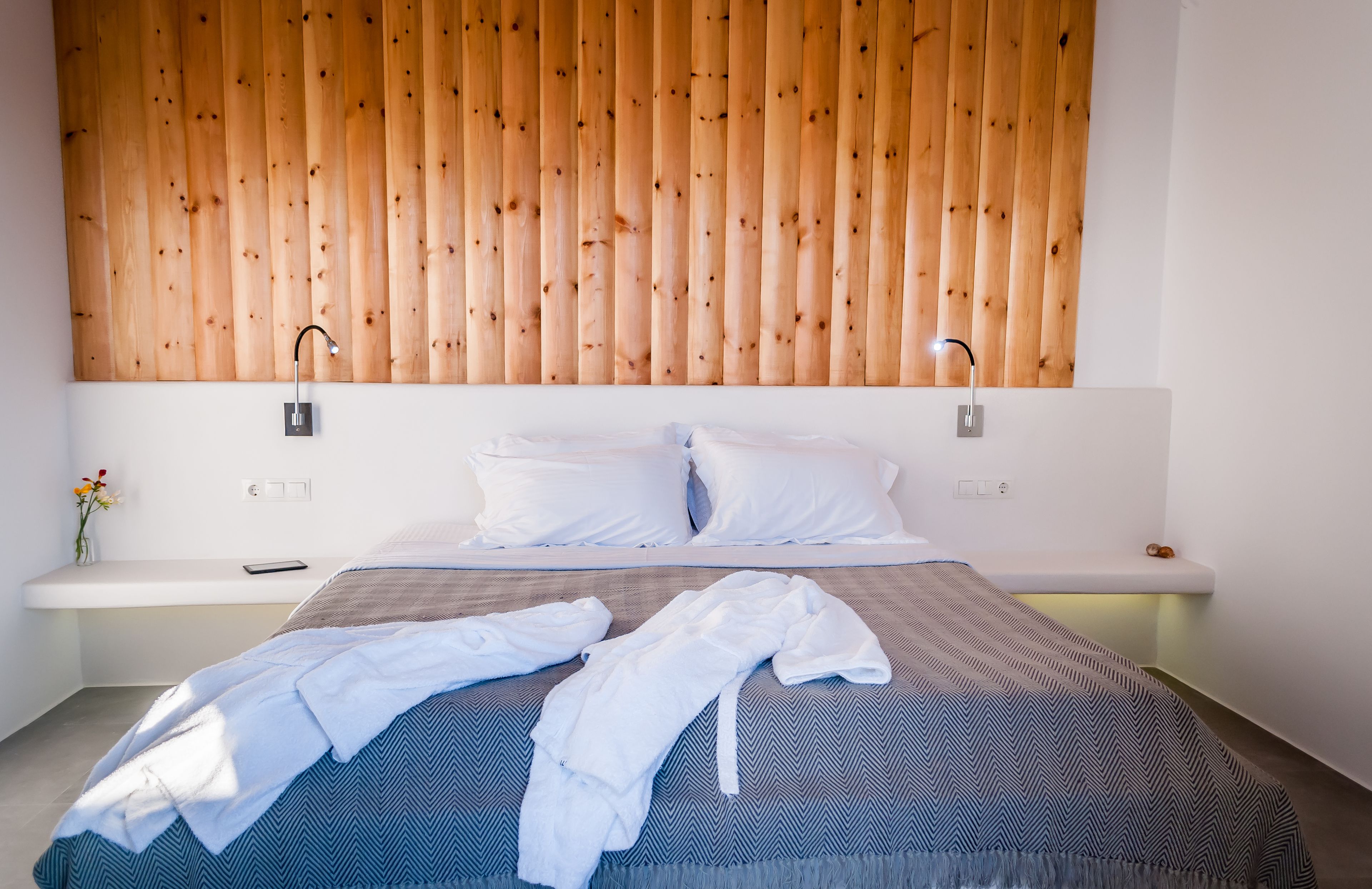 Un dormitorio moderno con cabecera de madera, una cama grande con colcha estampada y lámparas de noche.