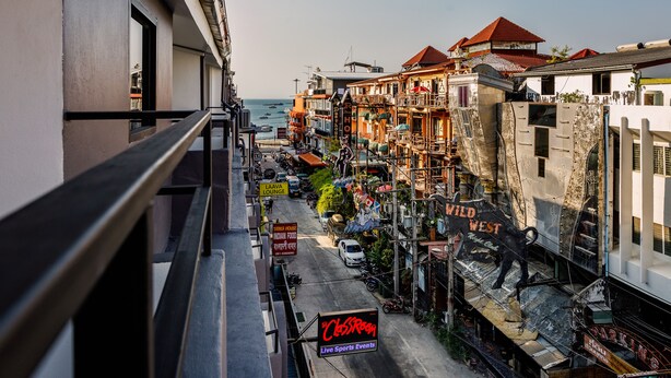 A street view with a building featuring a balcony and a sign for 'The Classroom Live Sports Events'. - The Classroom Hotel (Pattaya)