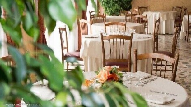 Un restaurante con mesas y sillas redondas, algunas con manteles blancos.